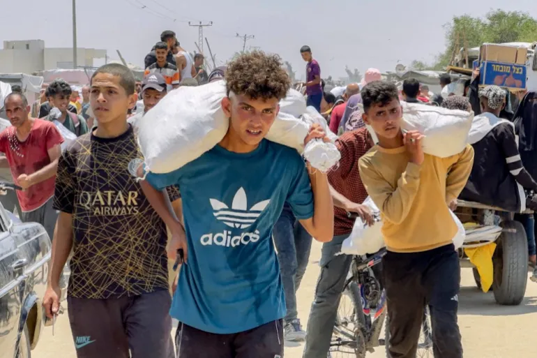 A war-affected boy in Gaza carries a sack of flour amid ongoing humanitarian crisis