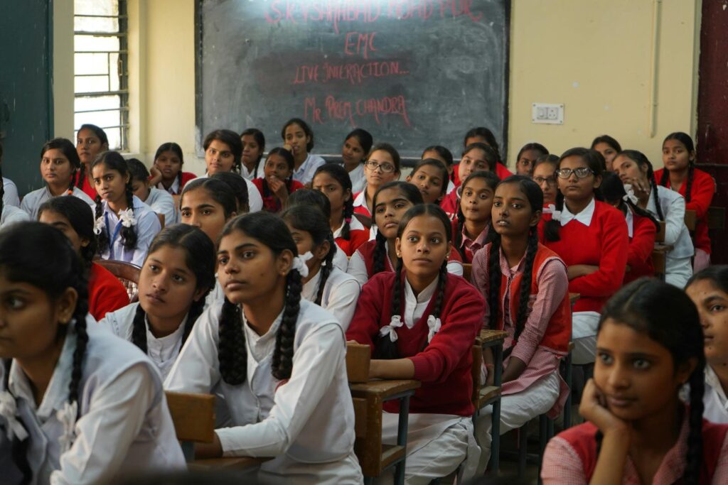A classroom full of attentive schoolgirls in uniform, seated at desks and listening intently during a session. This image reflects the engagement of young students in educational activities and highlights the importance of curriculum reform in shaping inclusive, participatory learning environments.