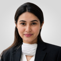 Professional headshot of a smiling woman with dark hair in a black blazer and white scarf.